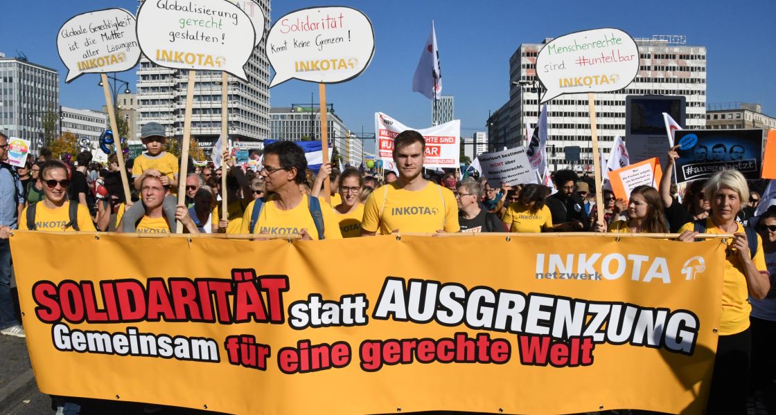 eine Menschenmenge mit einem großen Banner tragend und Protestschildern