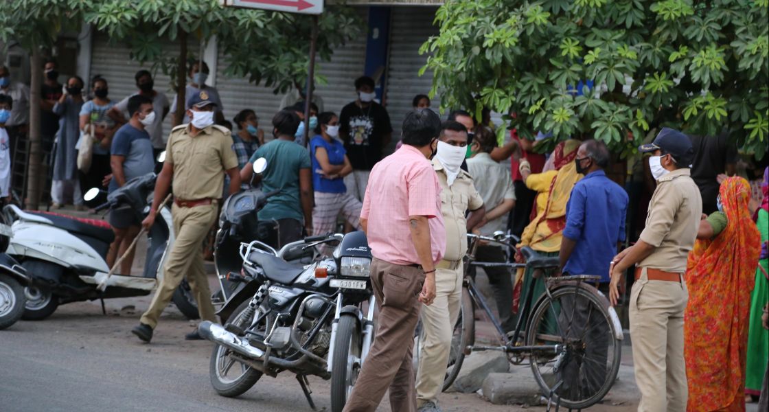 eine Straßenszene in Indien mit Menschen, Fahrrad, Motorrad und Polizist