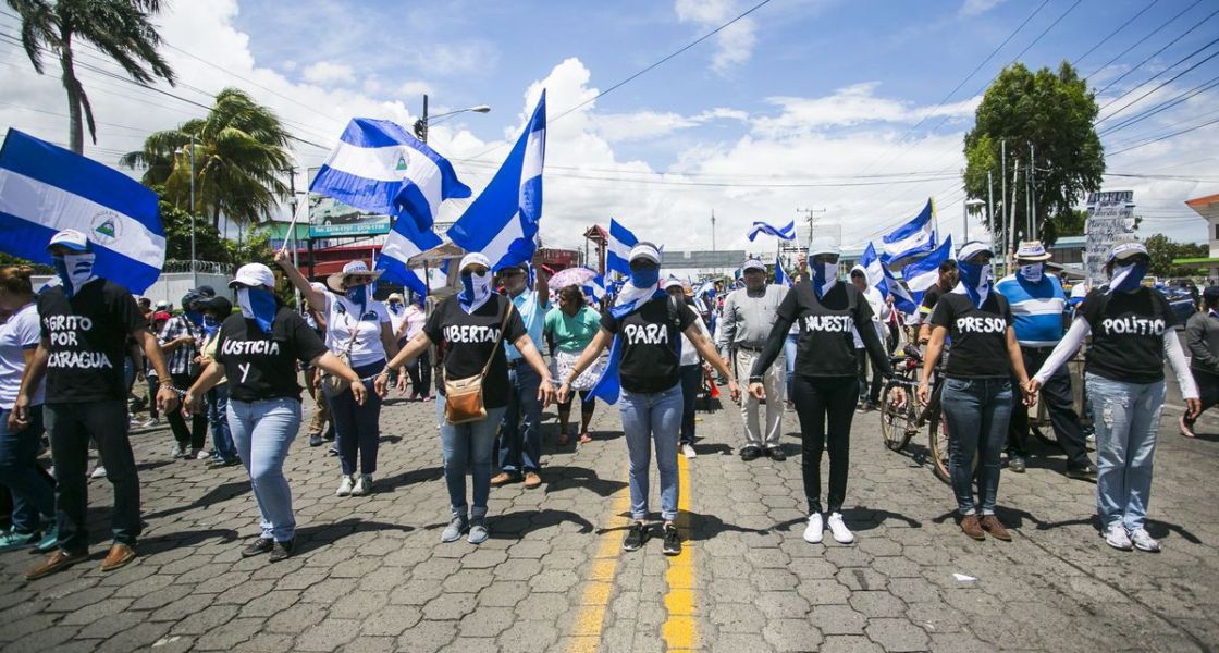 Menschen mit blau-weißen Tüchern bilden eine Kette und protestieren
