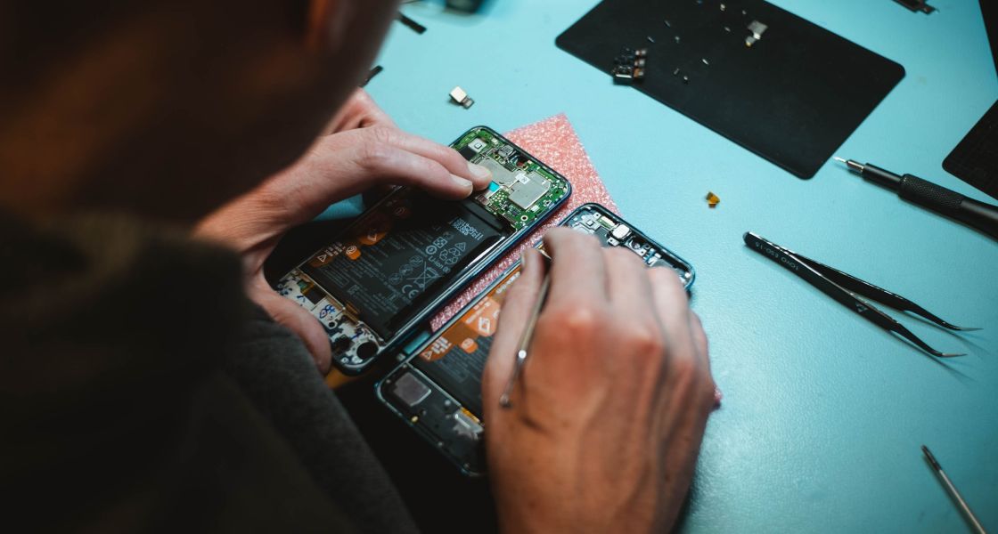 Ein Handy hält seine Hände mit einem Schraubenzieher auf ein geöffnetes Handy