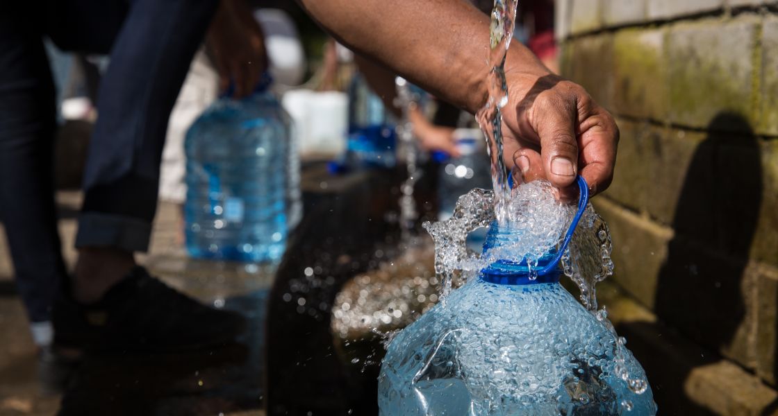 eine große Plastikflasche mit wird Wasser aus einem Hahn gefüllt