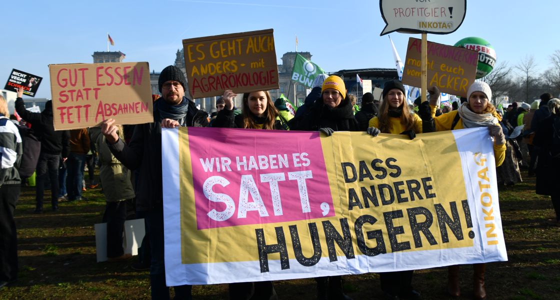 Demonstrierende halten ein Banner mit dem Text "Wir haben es satt, dass andere Hungern!"