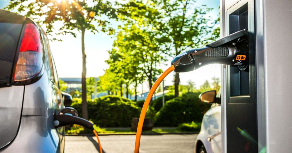 Ein Auto und eine Ladestation sind durch ein orangefarbenes Kabel verbunden
