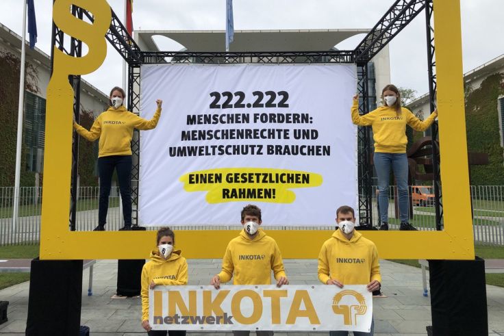 INKOTA-Mitarbeitende stehen mit einem großen Forderungs-Banner vor dem Kanzleramt in Berlin