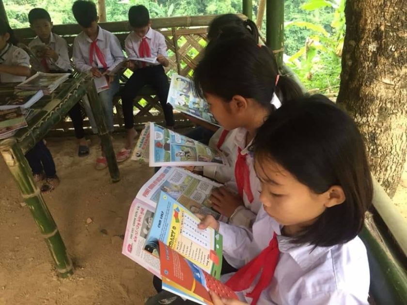 Kinder mit roten Halstüchern lesen in Schulheften