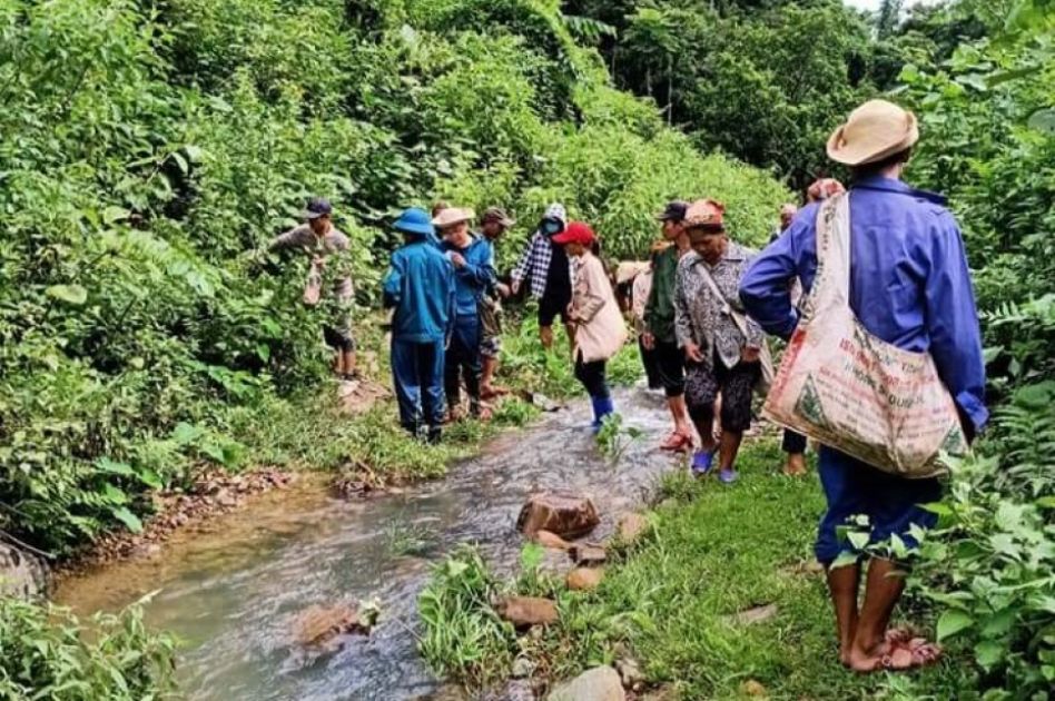Mehrere Frauen und Männer laufen an einem Fluss im Wald entlang