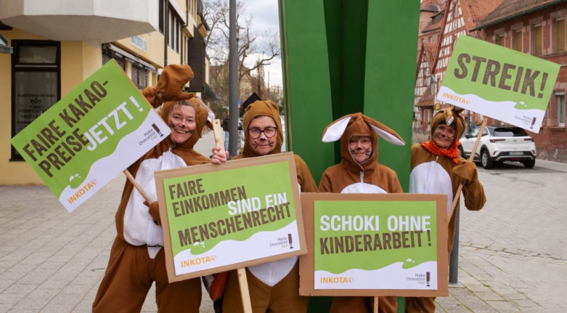 Vier Frauen in Osterhasenkostümen halten Protestschilder hoch