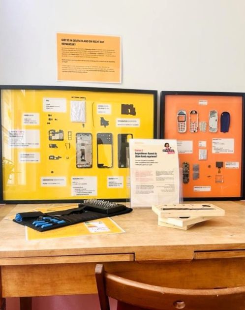 Foto mit auseinandergebauten Handys in einem Bilderrahmen. Die einzelnen Komponenten der Handys sind zu sehen. Außerdem ein Werkzeugset mit verschiedenen Schraubenschlüsselköpfen