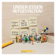 Eine Gruppe Miniaturmenschen stehen vor großen Plakaten