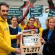 Ein Mann und eine Frau halten gemeinsam einen Holzkasten fest, auf dem die Anzahl der Unterschriften für eine Petition geschrieben steht