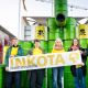Fünf INKOTA-Aktivist*innen stehen vor gelben und grünen Fässern, sie halten ein INKOTA-Banner in der Hand
