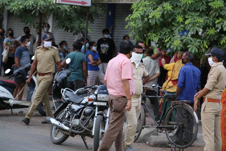 eine Straßenszene in Indien mit Menschen, Fahrrad, Motorrad und Polizist