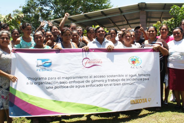 Eine Gruppe von Menschen in El Salvador halten ein großes Banner hoch