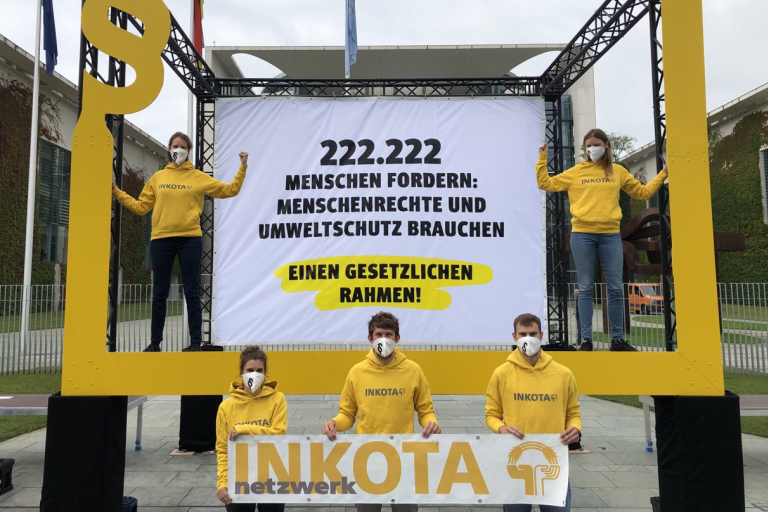 INKOTA-Mitarbeitende stehen mit einem großen Forderungs-Banner vor dem Kanzleramt in Berlin
