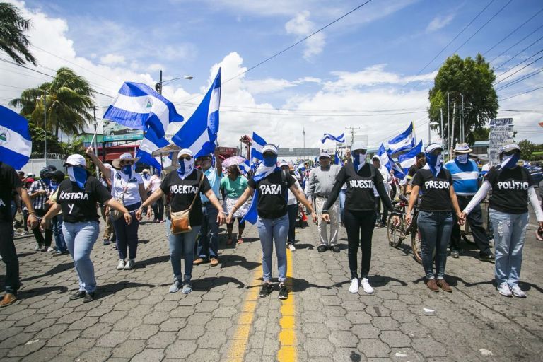 Menschen mit blau-weißen Tüchern bilden eine Kette und protestieren