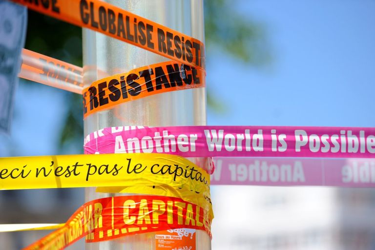 bunte Protestslogans auf Plastikbändern um einen Mast gewickelt