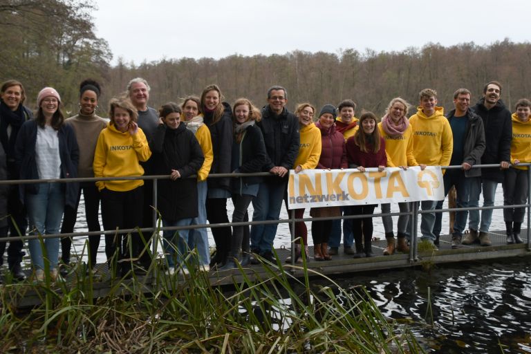 Inkota-Mitarbeiter*innen stehen auf einem Steg an einem See